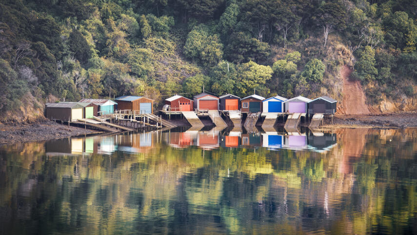 Boat sheds reflecting on the still Akaroa harbour